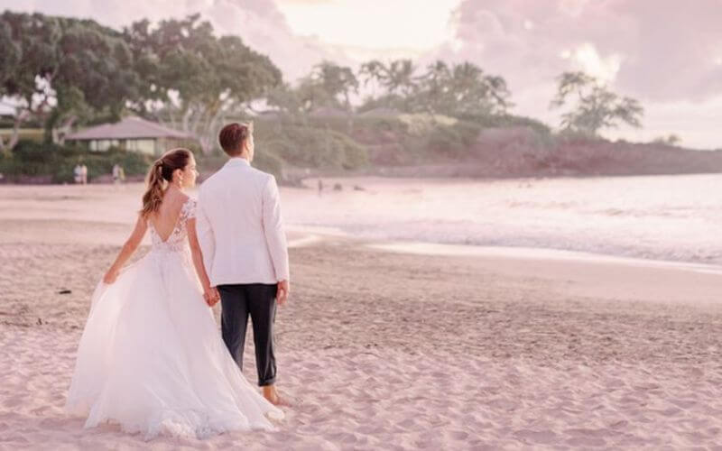 Bride and groom walking on beach 