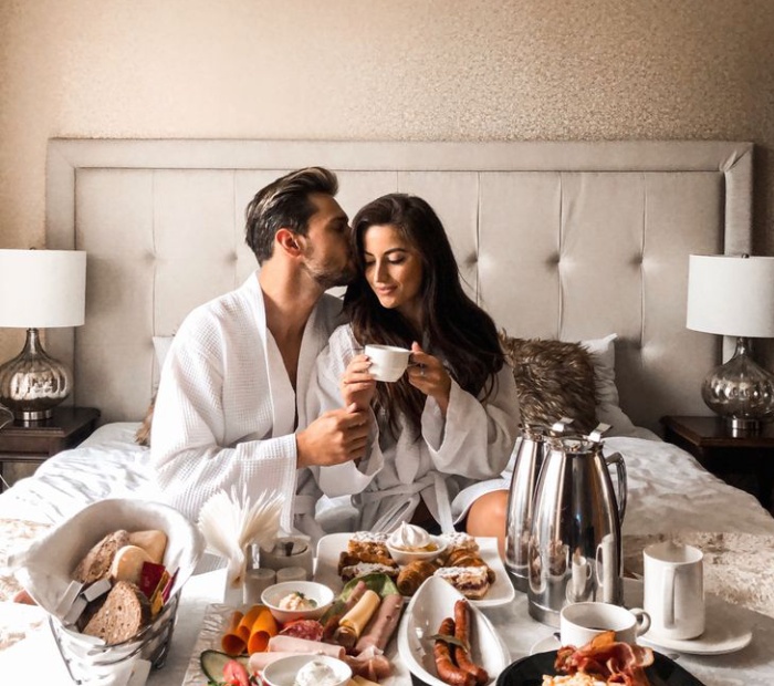 Husband and wife sharing a romantic breakfast in bed at home.