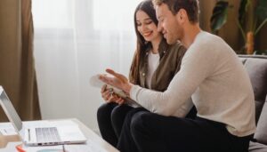 Newlywed Financial Planning: Build a Secure Future Together Newlywed couple sitting together at home reviewing financial documents and a laptop, smiling while planning their budget and future finances together.