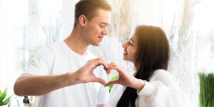 Married couple smiling and forming a heart shape with their hands, representing intimacy in marriage and emotional connection.