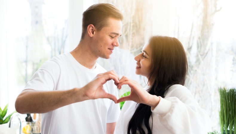 Married couple smiling and forming a heart shape with their hands, representing intimacy in marriage and emotional connection.