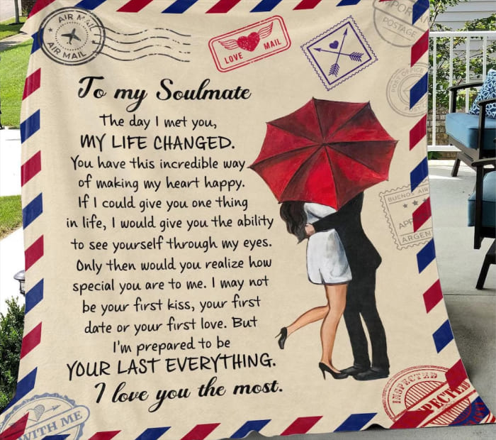 Woman holding a large romantic “To my soulmate” blanket featuring a love letter design with a couple kissing under a red umbrella and vintage airmail border.