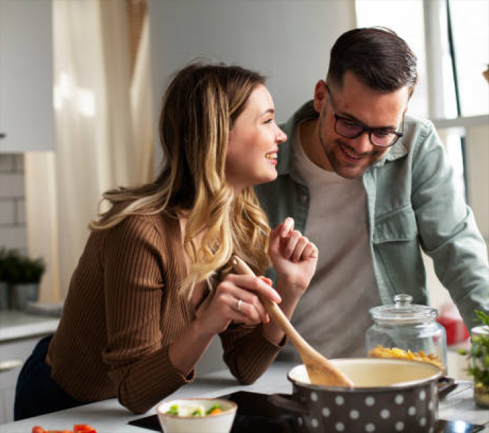 Cooking Together: Happy couple smiling while cooking a meal in a kitchen.
