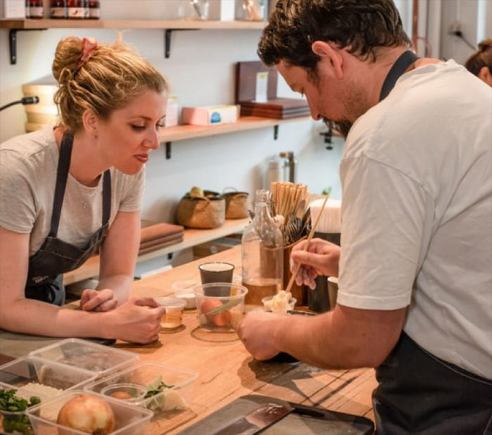 Couple cooking together in a kitchen, preparing ingredients side by side, showcasing a fun and meaningful Valentine’s Day experience gift.