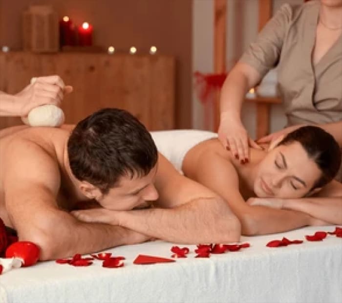 Couple enjoying a romantic spa massage together with rose petals and candles, representing a relaxing and intimate Valentine’s Day experience gift.