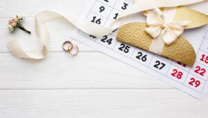 March 2026 wedding calendar with gold rings and invitation on white background