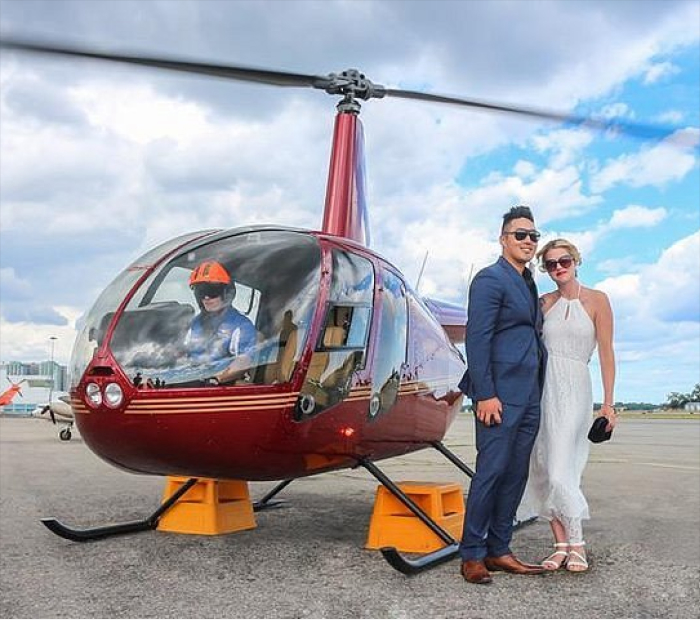 Couple posing beside a helicopter before a scenic flight, highlighting an adventurous and luxurious Valentine’s Day experience gift.