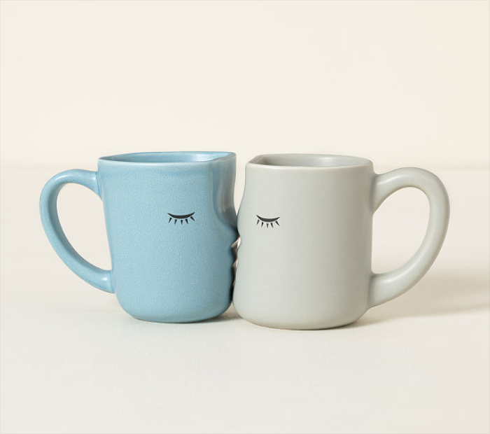 Set of two romantic couple mugs in blue and gray, placed side by side with simple eyelash face designs.
