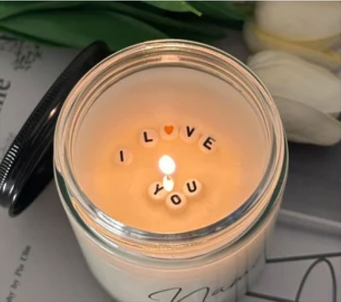 Message Candle: Lit candle with "I Love You" letter beads in wax.
