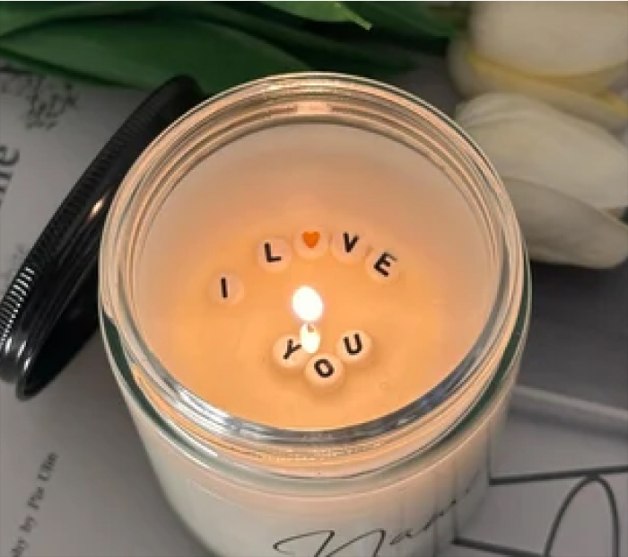 Message Candle: Lit candle with "I Love You" letter beads in wax.