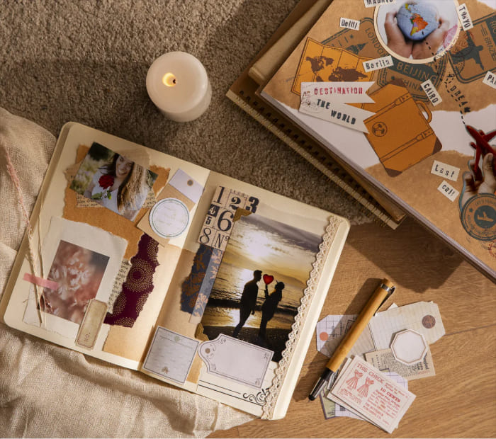 A romantic travel-themed scrapbook next to a lit candle.