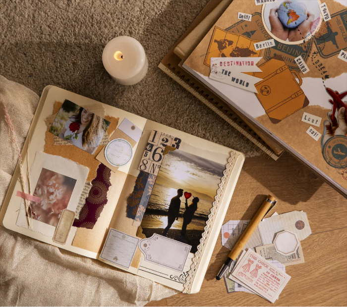 A romantic travel-themed scrapbook next to a lit candle.