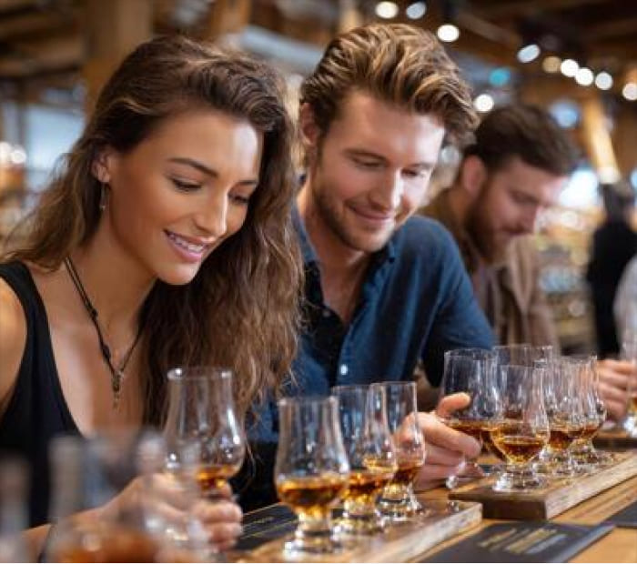 Couple enjoying a romantic whiskey tasting experience together, sharing drinks and smiles in a warm, intimate setting
