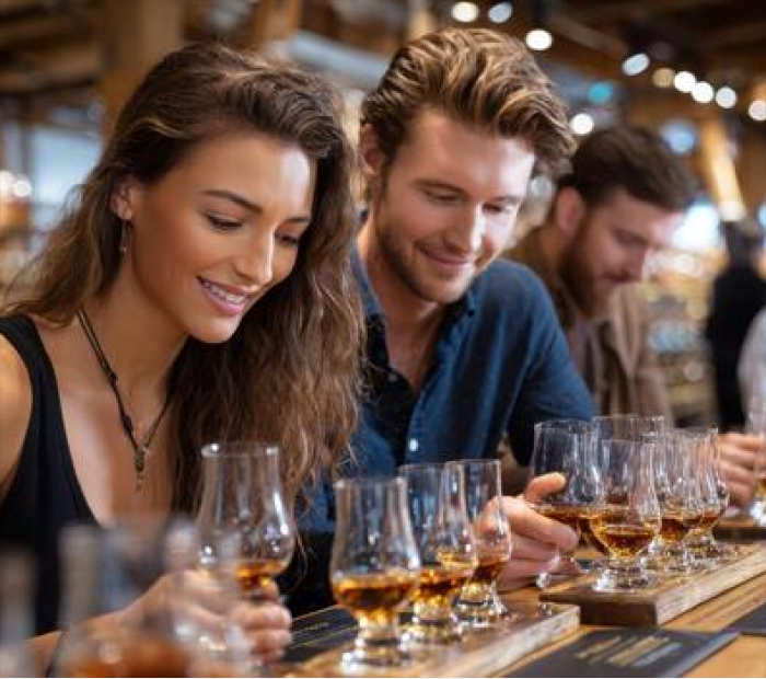 Couple enjoying a romantic whiskey tasting experience together, sharing drinks and smiles in a warm, intimate setting