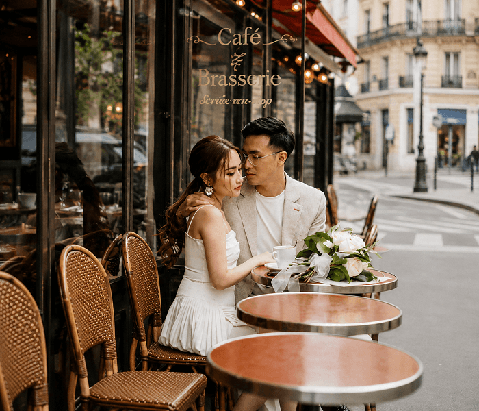 Propose in a Parisian Café - Happy Wedding App A couple shares an intimate moment at a Parisian café surrounded by flowers.