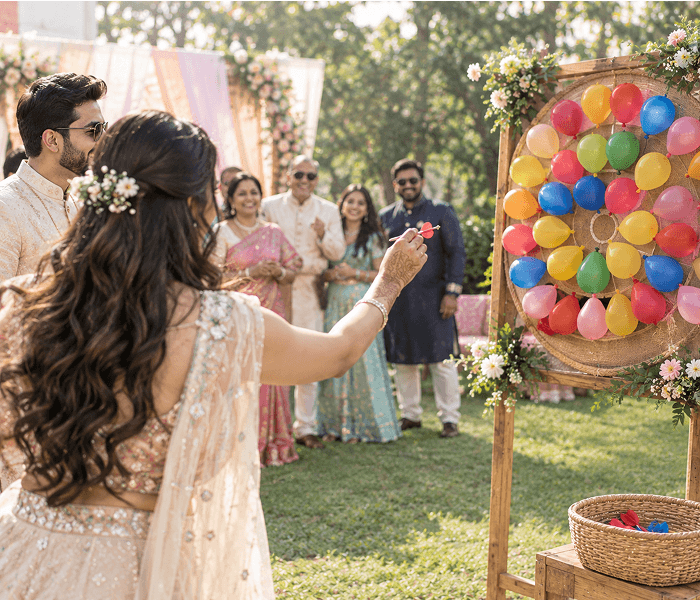 Balloon Pop Dart Throw - Happy Wedding App A woman throwing a dart at a circular target board covered in colorful balloons outdoors.