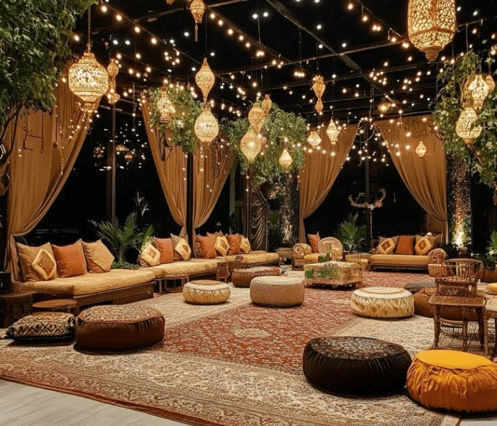 Bollywood Carnival Night - Happy Wedding App Dimly lit night venue decorated with hanging brass lanterns, string lights, patterned carpets, and low floor cushions.