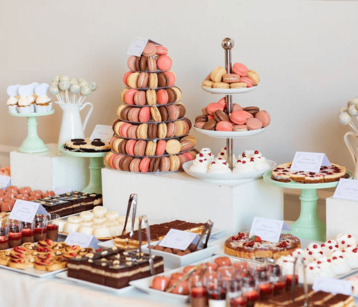 Candy Grab Booth - Happy Wedding App A dessert table filled with a macaron tower, pastry tiers, cakes, and mini dessert cups.
