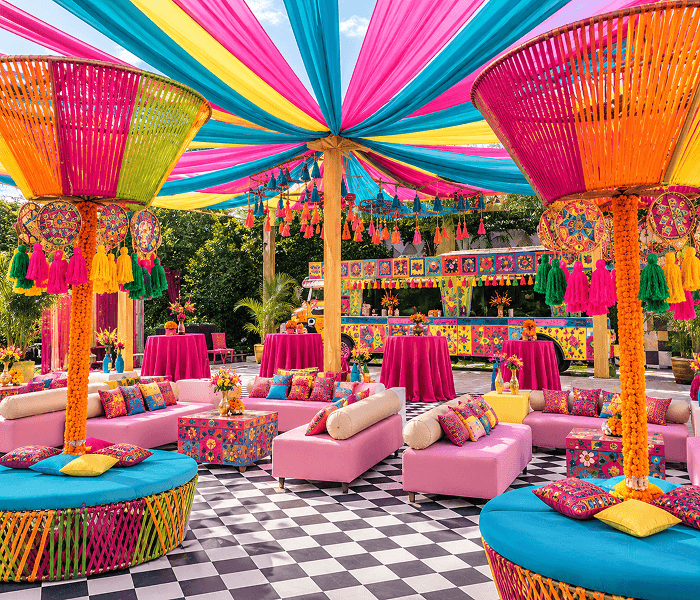 Vintage Mela Traditional Indian Fair Carnival - Happy Wedding App Vibrant outdoor event area with colorful ceiling drapes, pink sofas, bright cushions, and a decorated food truck.